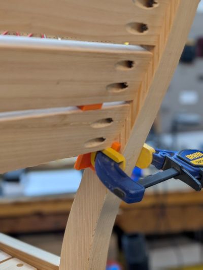 an image of a jig holding a slat in place from the back of the bench